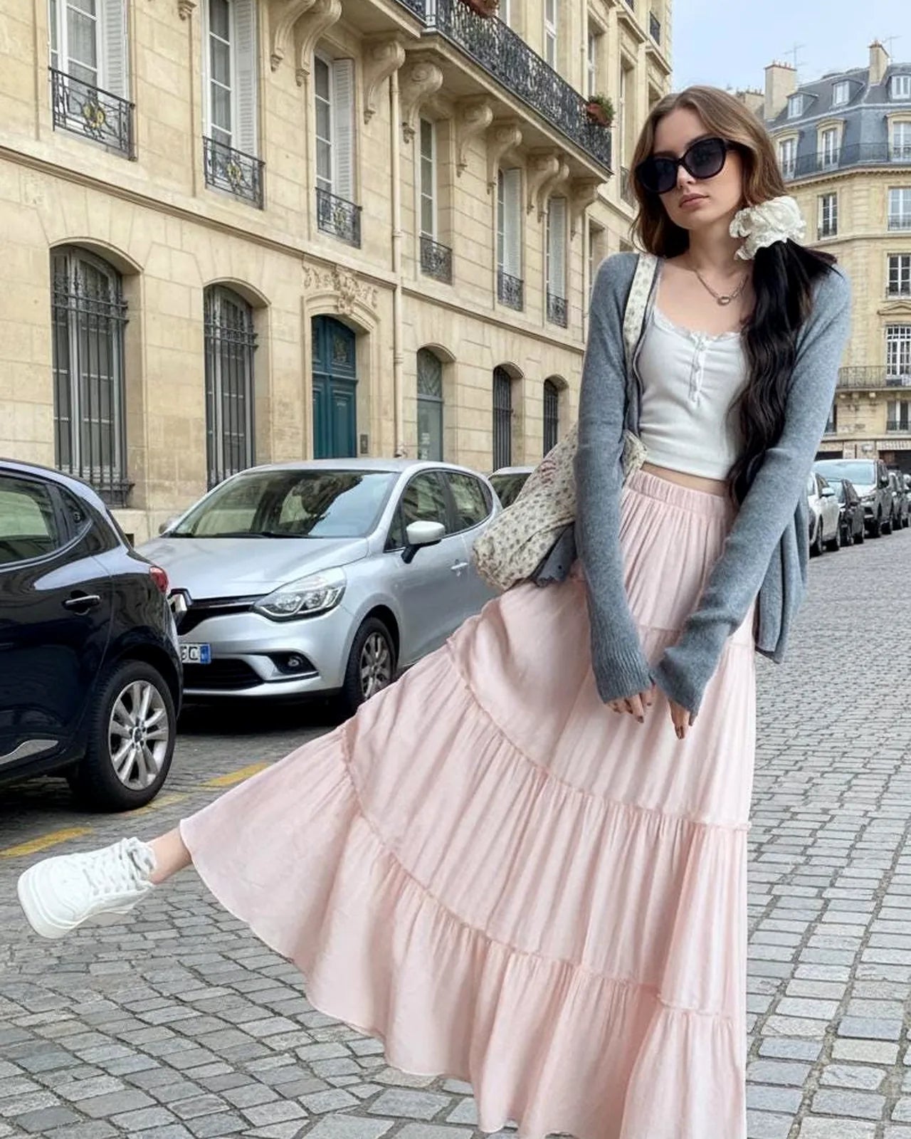 Model crossing a Paris street in a pink tiered maxi skirt and grey cardigan.